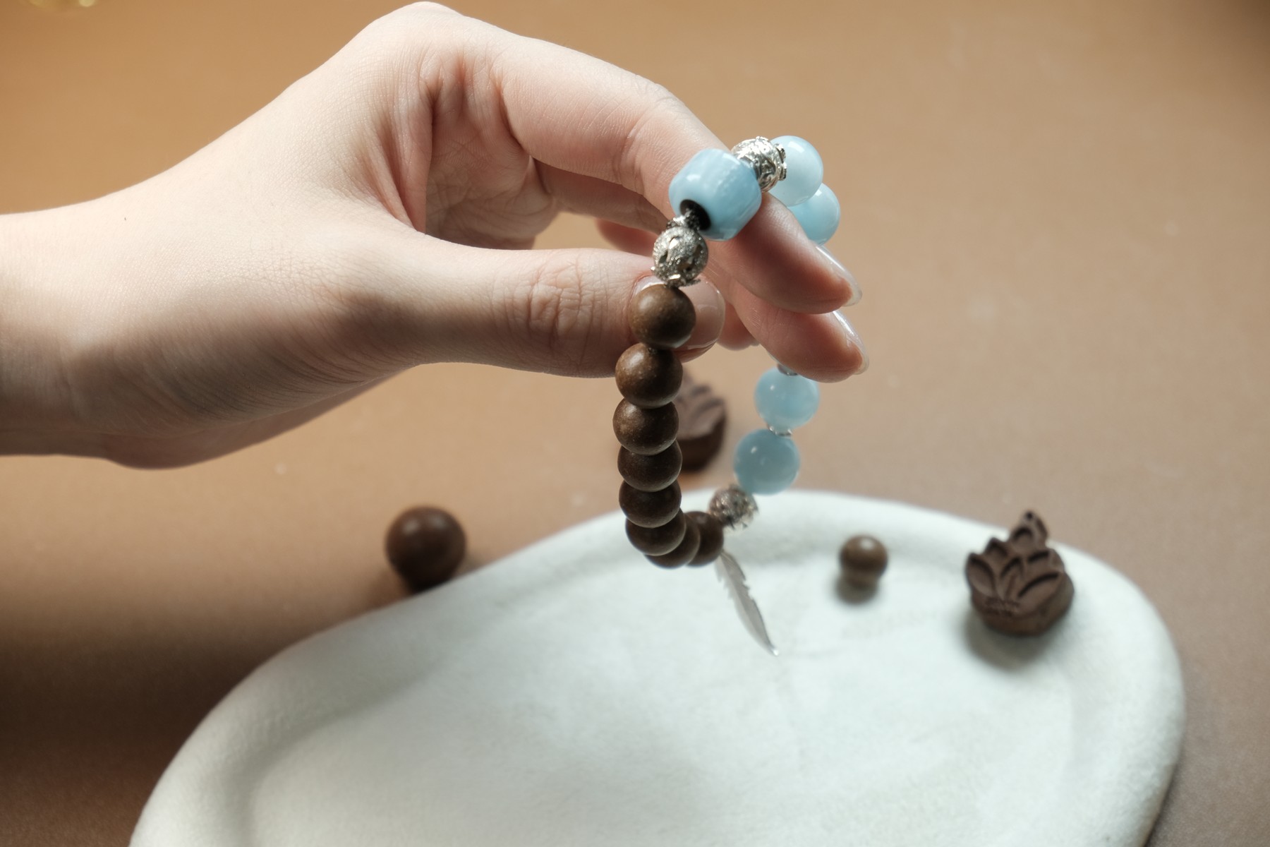 An incense bead bracelet with blue accent beads, held in the hand